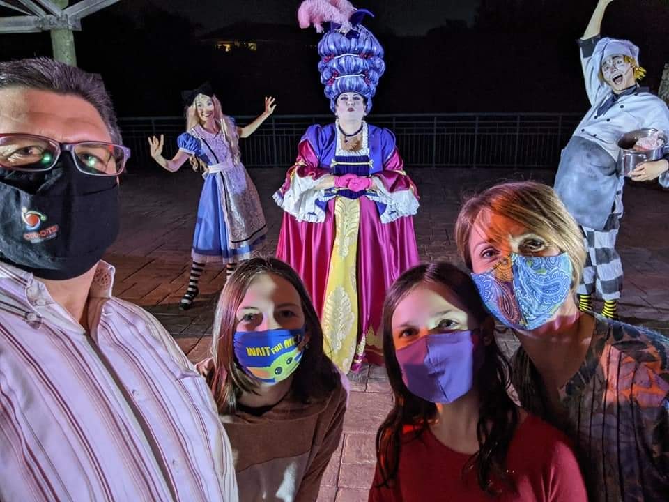 People posing with costumed characters at night event